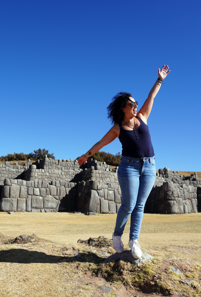 Viaje en grupo a Peru, donde la coordinadora se ve saltando en sacsayhuaman, ruinas Inca en los alrededores de Cusco