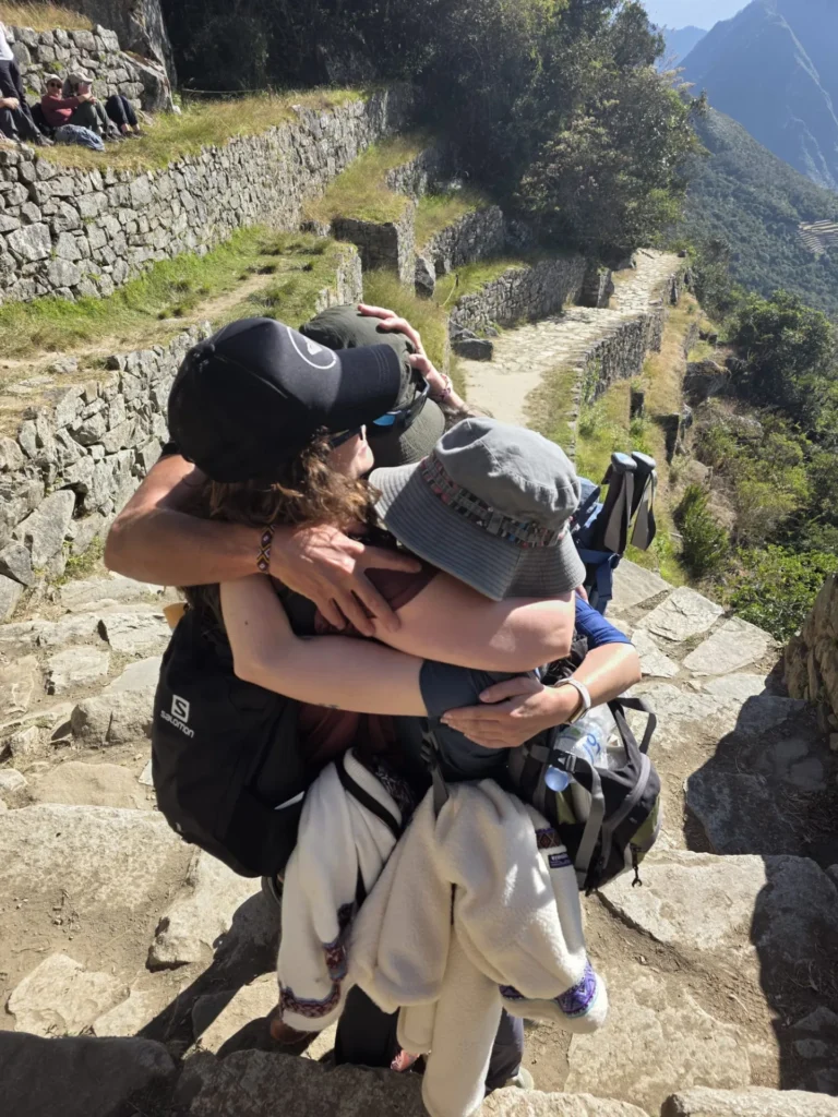 Grupo de viajeros abrazandose en la puerta del sol del Camino Inca, puerta de acceso a MachuPicchu